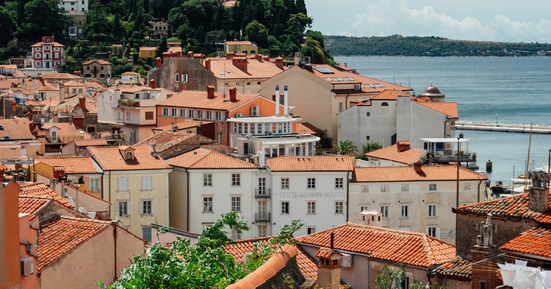 Terracotta rooftops and pastel waterfront homes in a European coastal town